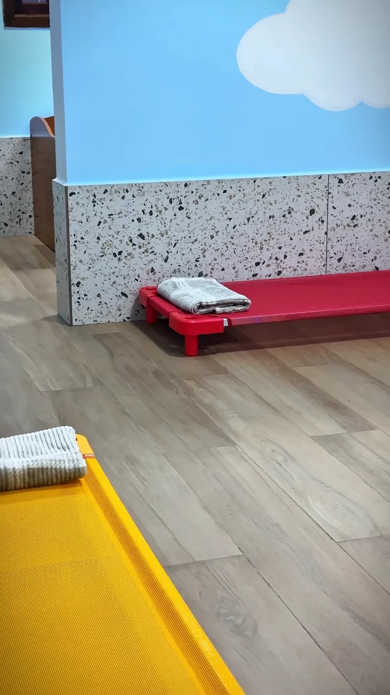 Detalhe do quarto: caminha vermelha com manta dobrada e parede de nuvens